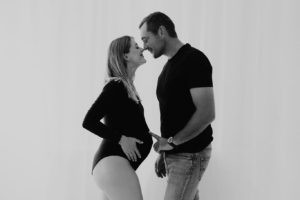 babybauch12 Ein Paar im Studio bei einem schlichten, herzlichen Babybauchshooting, in dem beide sowohl liegend als auch sitzend fotografiert werden, mit Fokus auf Nähe und Vorfreude