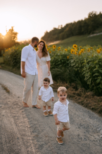 Familie mit Zwillingen im Freien bei Sonnenuntergang inmitten von Sonnenblumen