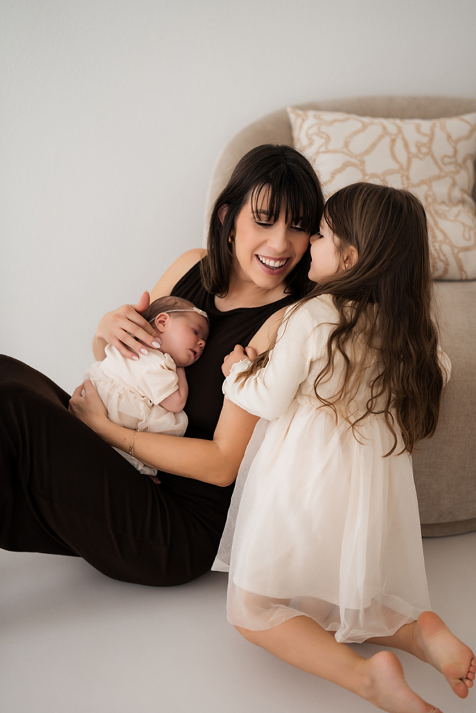 babyfotos12 Fürsorgliche große Schwester hält das Baby im Arm während eines natürlichen Studioshootings.