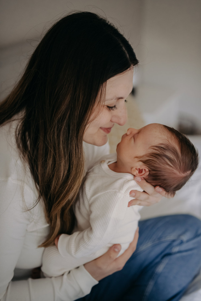 homestory-11 Neugeborenes schläft in den Armen der Mutter bei einer Homestory in der Steiermark. Zeitloses und schlichtes Neugeborenenshooting.