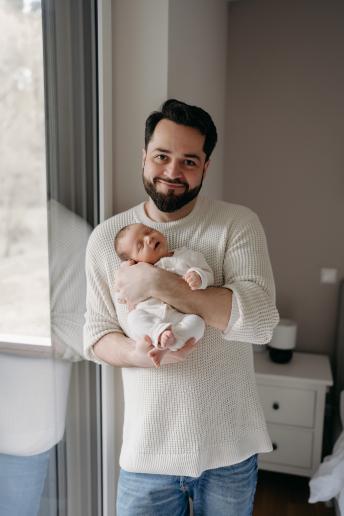 homestory-13 Neugeborenes schläft in den Armen des Vaters bei einer Homestory in der Steiermark. Zeitloses und schlichtes Neugeborenenshooting.