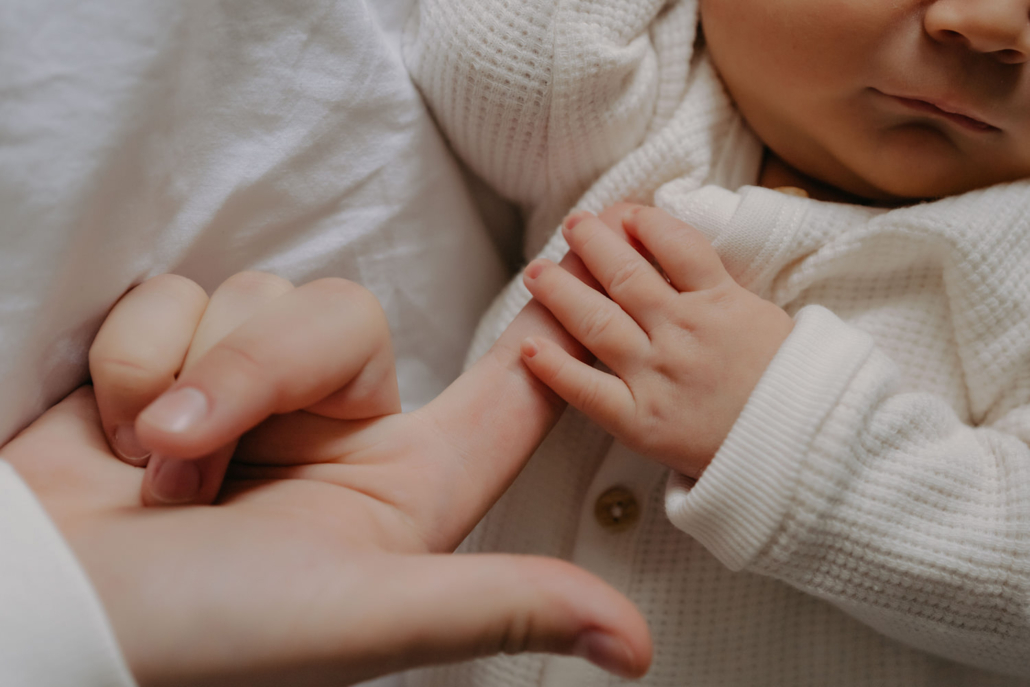 homestory-18 Geschwistermoment: ältere Schwester hält das Neugeborene liebevoll im Arm, authentisches Familienshooting zu Hause.