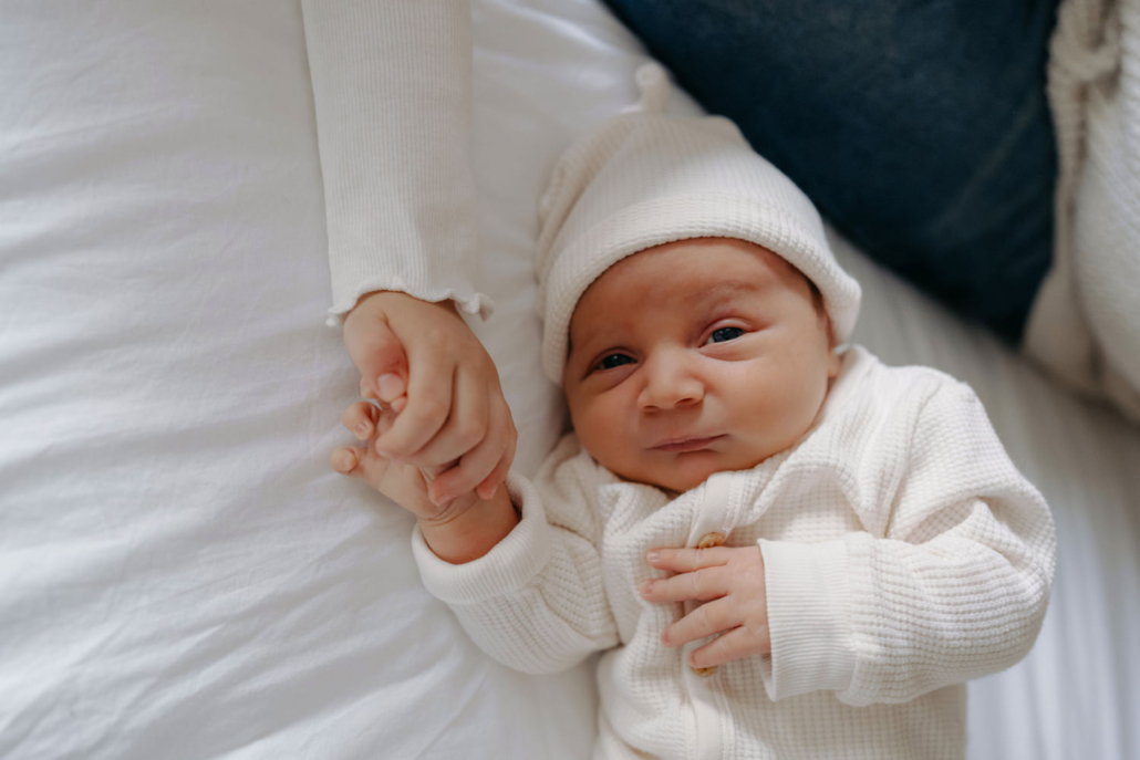 homestory-6 Geschwistermoment: ältere Schwester hält das Neugeborene liebevoll im Arm, authentisches Familienshooting zu Hause.